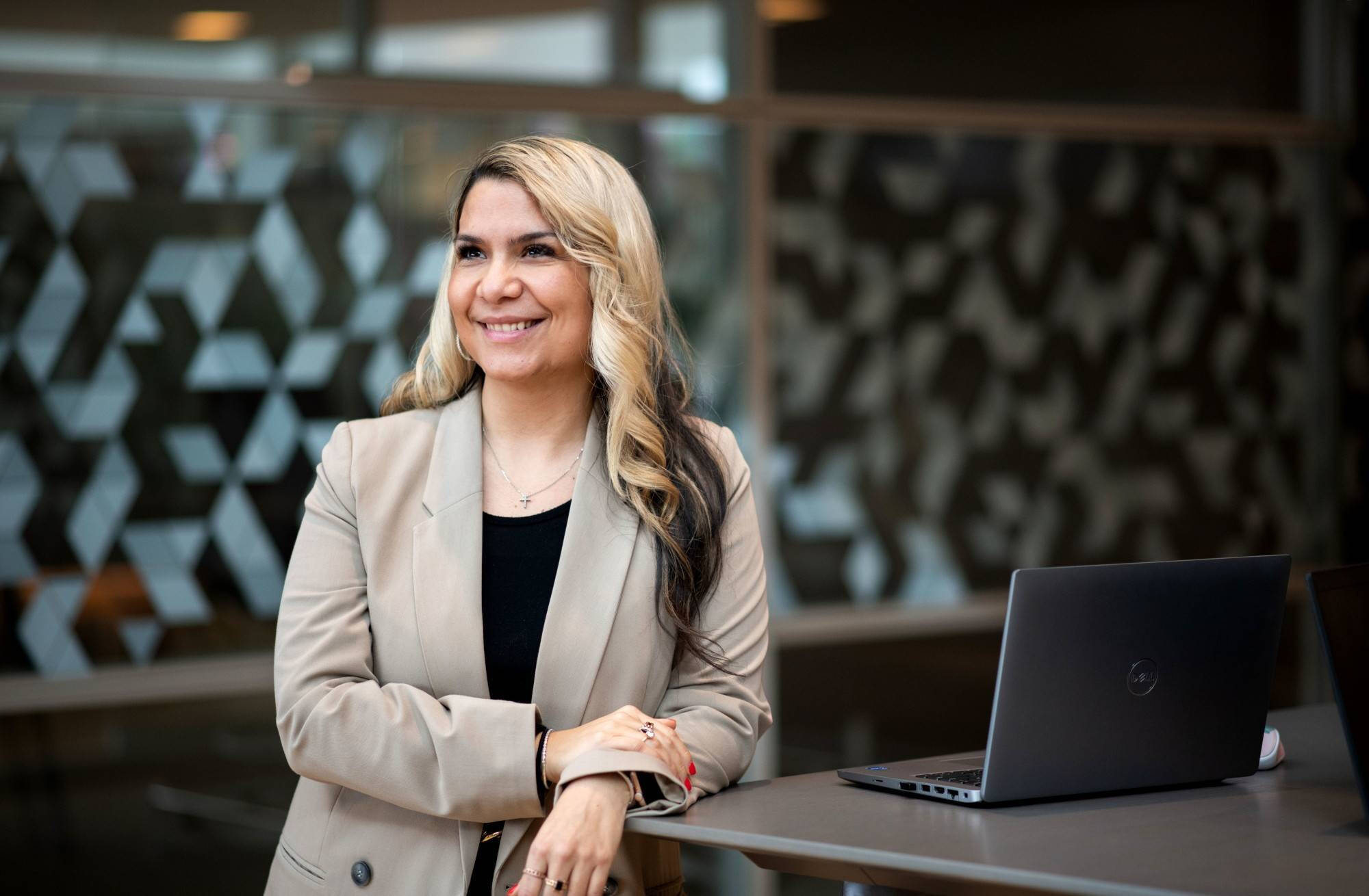 Woman in a blazer next to a laptop